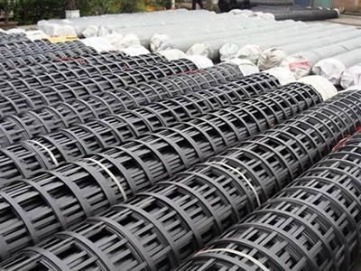 Several black color composite mine supporting meshes with woven bag at both ends on the ground.