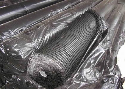 Many rolls of fiberglass geogrid in plastic bags.