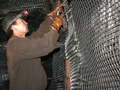 A worker is installing the bilateral stretched plastic mesh onto roadway sidewall.